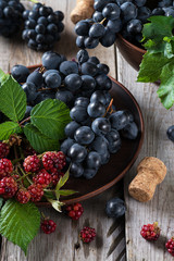Fresh grapes in a clay plate on a wooden old table..