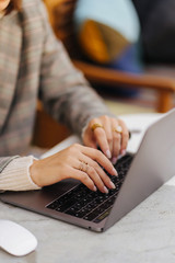 Close up image of woman hands typing and writing on laptop, working on cafe.