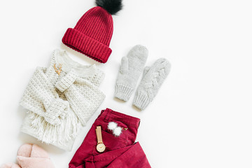 Obraz na płótnie Canvas Gray warm knitted sweater, mittens with vinous winter hat and trouserson on white background. Women's stylish autumn or winter clothes. Flat lay, top view.