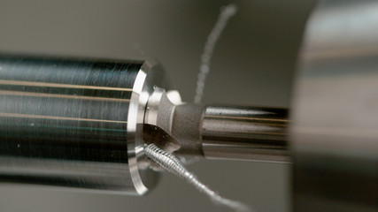 MACRO, DOF: Sharp drill bores a hole into the middle of a shiny aluminium rod.