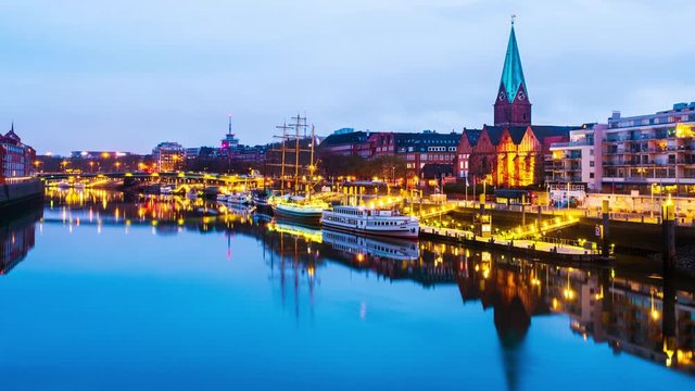 Bremen, Germany. View of the cityscape of Bremen, Germany at sunrise. Time-lapse from dark to bright of illuminated landmarks and river, reflection in the water