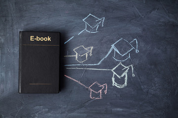 E-learning and online education or web lesson. E-library and e-book. Book on blackboard and graduate cap.