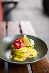 Pancakes topped with savory sauce and smoked salmon. Close up view.