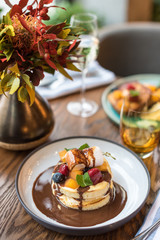 Pancakes topped with chocolate sauce, fresh fruit and berries. Breakfast in restaurant