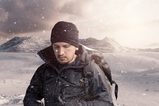 tired hiker with trekking poles and hiking rucksack breathe out in front of rocky landscape
