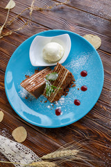 Ice cream and cake on a blue plate on a brown wooden background