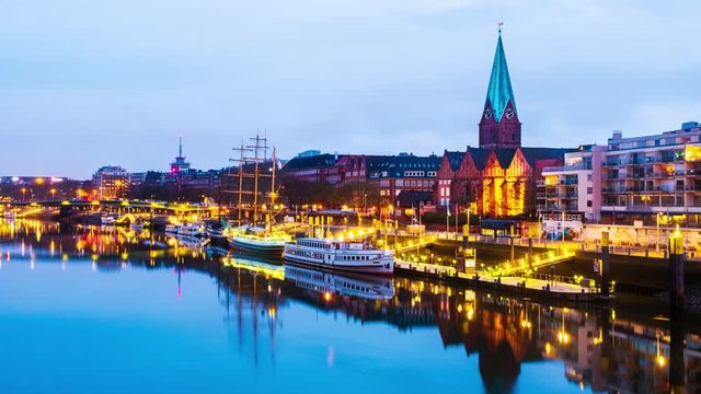 Bremen, Germany. View of the cityscape of Bremen, Germany at sunrise. Time-lapse from dark to bright of illuminated landmarks and river, reflection in the water, zoom in