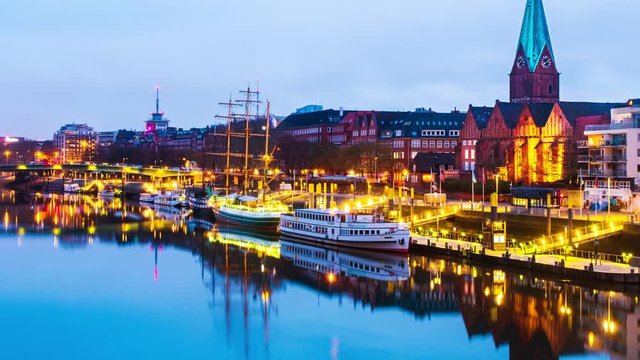 Bremen, Germany. View of the cityscape of Bremen, Germany at sunrise. Time-lapse from dark to bright of illuminated landmarks and river, reflection in the water, panning video