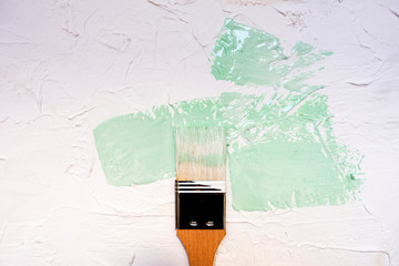 Brush with wooden handle with gentle breeze paint on white putty textured background. Neo mint...
