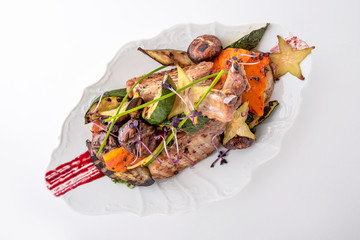 Roast pork or lamb with grilled vegetables and exotic fruits. Banquet festive dishes. Fine dining restaurant menu. White background.