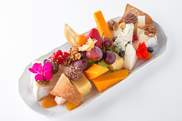 Cheese platter with different cheeses, grapes, nuts, honey, bread and dates. Banquet festive dishes. Gourmet restaurant menu. White background.