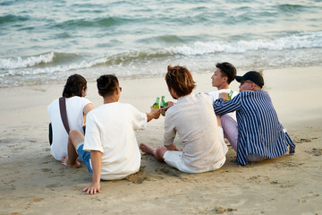 group of asian men drinking beer on beach