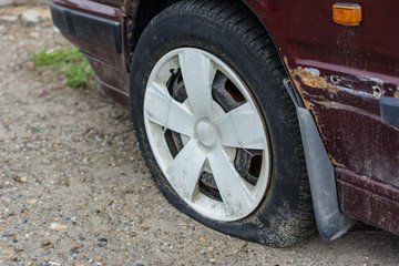 Damaged tire. The wheel of car tire leak. Flat tire on the off-road waiting for repair.