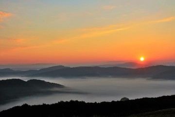 sunset over mountains with fog in the valleys