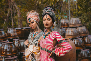 two beautiful stylish woman wearing turban surrounded by pots