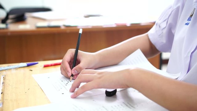 Student testing in exam on exercise sheet, taking at school or university in test room, writing document exams paper at campus classroom, education back to school or evaluation and measurement concept
