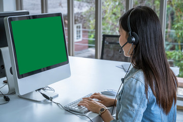 Call center woman sitting in customer service office in front of the computer, green screen with...