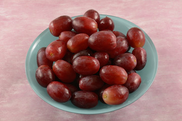 Freshly rinsed red grapes removed from stem in blue bowl