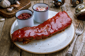 Barbecue pork ribs with beans and coleslaw on old wooden table