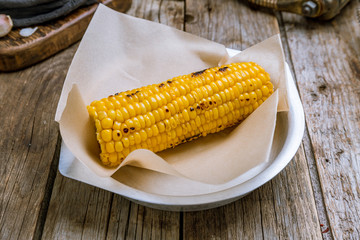 Baked corn on a plate on old wooden table