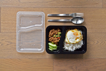 Spoon and fork and black rice box with clear lid, add fried rice with basil this food is a popular...