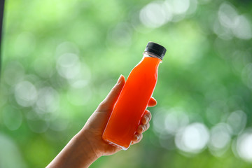 Healthy fruit juice in clear plastic bottles, the background is a green garden and bokeh.