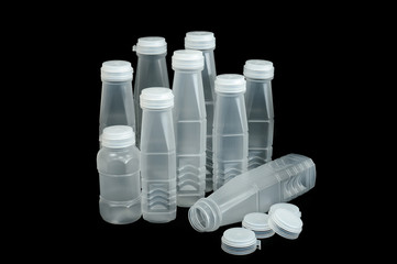 Plastic bottles and plastic caps of many sizes are placed together on a black background.