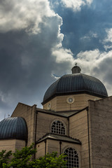 Sunshine through clouds on greek orthodox church building and dome peaked with cross in Greenville, SC