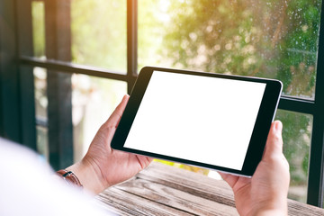 Mockup image of hands holding black tablet pc with blank white desktop screen
