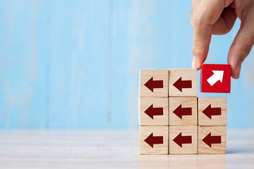 Businessman hand placing or pulling Red block with different direction of arrow on table background. Business Growth, Improvement, strategy, Successful, different and Unique Concepts