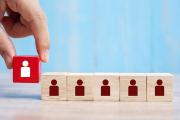Business man hand placing or pulling Red wooden block with white person icon on the building. People, Business, Human resource management, Recruitment, Teamwork, strategy and leadership Concepts