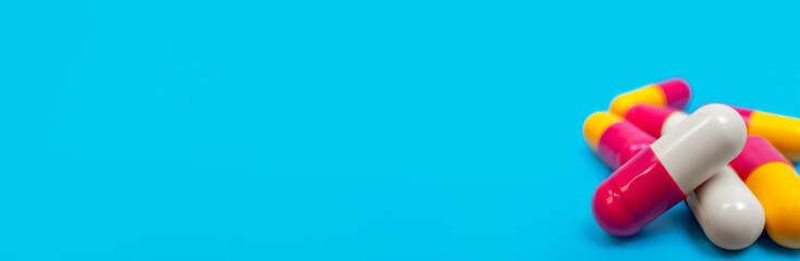 Medicine red, white and yellow pills or capsules on blue background with copy space.  Antibiotic drug prescription for treatment medication. Pharmaceutical medicament, cure in container for health.