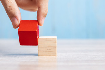 Businessman hand placing or pulling Red wooden block on the building. Business planning, Risk Management, Solution, strategy, different and Unique Concepts