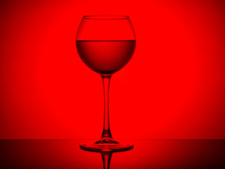 Wine glass with a drink on a red light background