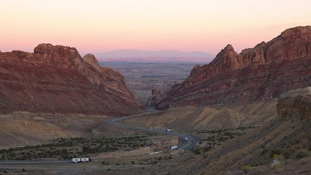 Time lapse of traffic driving through the desert on windy road at dusk viewing color landscape in Utah.