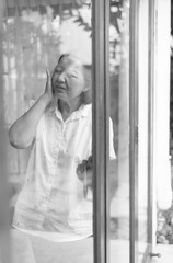 Senior healthy concept,Mature Asian elderly woman having migraine and headache pain near window at home,Black and white toned