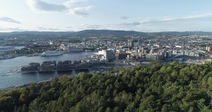 Cinema 4K drone shot with forward reveal motion and panorama view of the Oslo city tree line and construction in Bjoervika, a tourist attraction with the Munch museum, Soerenga and Barcode, in Norway.