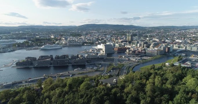 Cinema 4K drone shot with forward reveal motion and panorama view of the Oslo city tree line and construction in Bjoervika, a tourist attraction with the Munch museum, Soerenga and Barcode, in Norway.