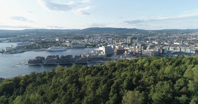 Cinema 4K drone shot with forward reveal motion and panorama view of the Oslo city tree line and construction in Bjoervika, a tourist attraction with the Munch museum, Soerenga and Barcode, in Norway.