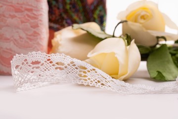 Fototapeta na wymiar Handiwork lace ribbon on the table among roses