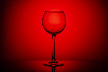 Wine glass with a drink on a red light background