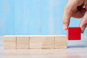 Businessman hand placing or pulling Red wooden block on the building. Business planning, Risk Management, Solution, strategy, different and Unique Concepts
