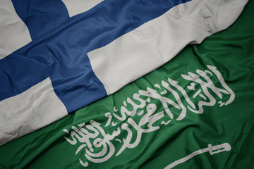 waving colorful flag of saudi arabia and national flag of finland.