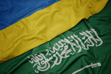 waving colorful flag of saudi arabia and national flag of ukraine.