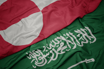 waving colorful flag of saudi arabia and national flag of greenland.