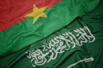 waving colorful flag of saudi arabia and national flag of burkina faso.