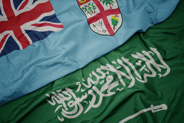 waving colorful flag of saudi arabia and national flag of Fiji .