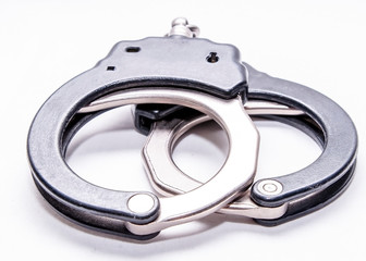 A pair of black and silver metal handcuffs on a white background