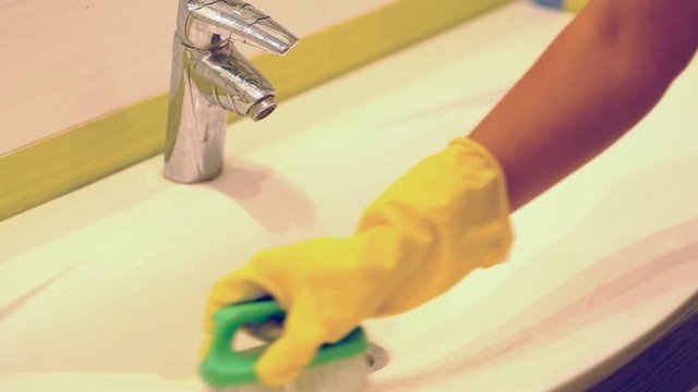 slow motion. Woman doing chores in bathroom at home, cleaning sink and faucet with spray detergent. Cropped view