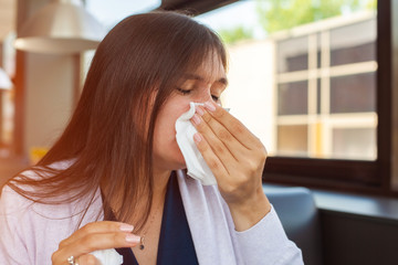 Brunette woman blowing nose into tissue